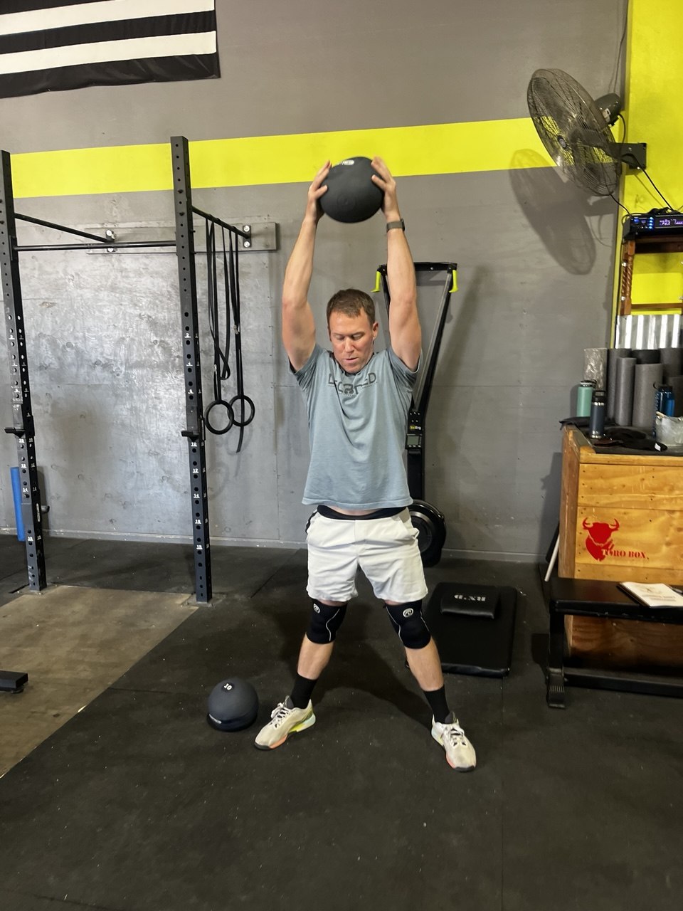 Member pressing a medicine ball overhead mid-workout