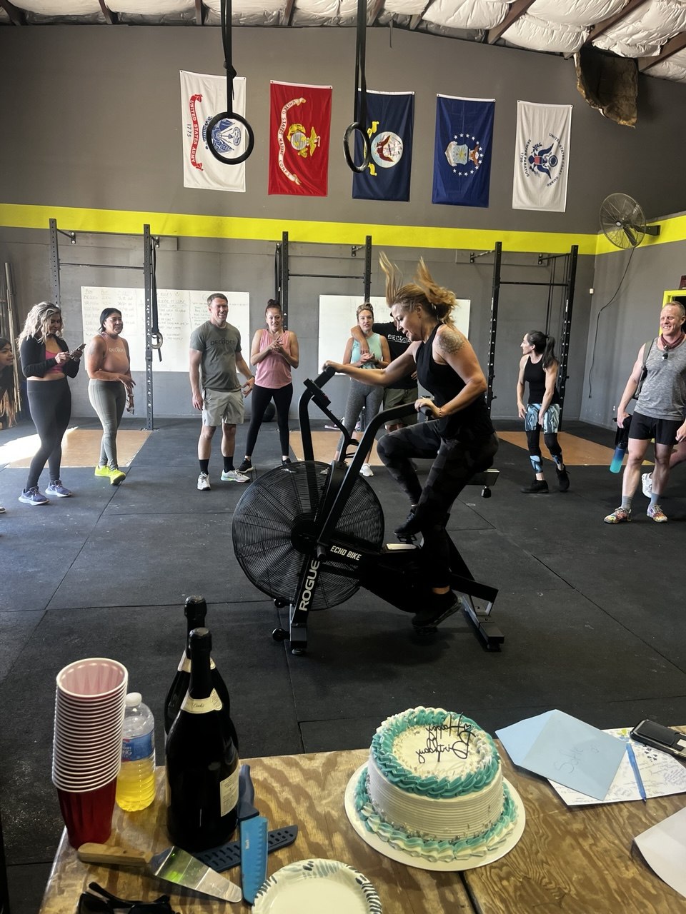 Member on the air bike with a celebration cake and champagne on the table