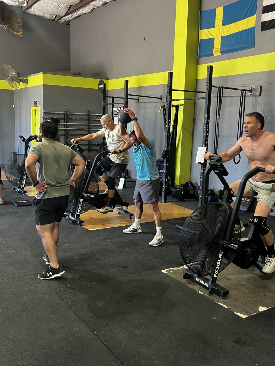 Members working the floor during a class, med ball and bike