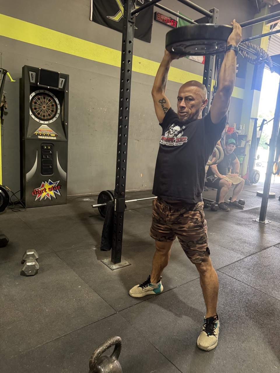 Member pressing a bumper plate straight overhead