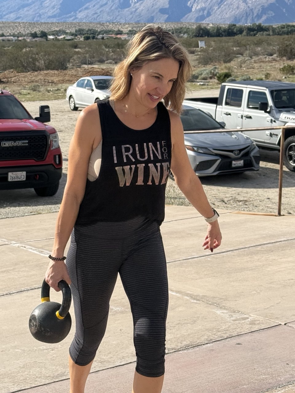 Member carrying a kettlebell outside with the desert mountains behind