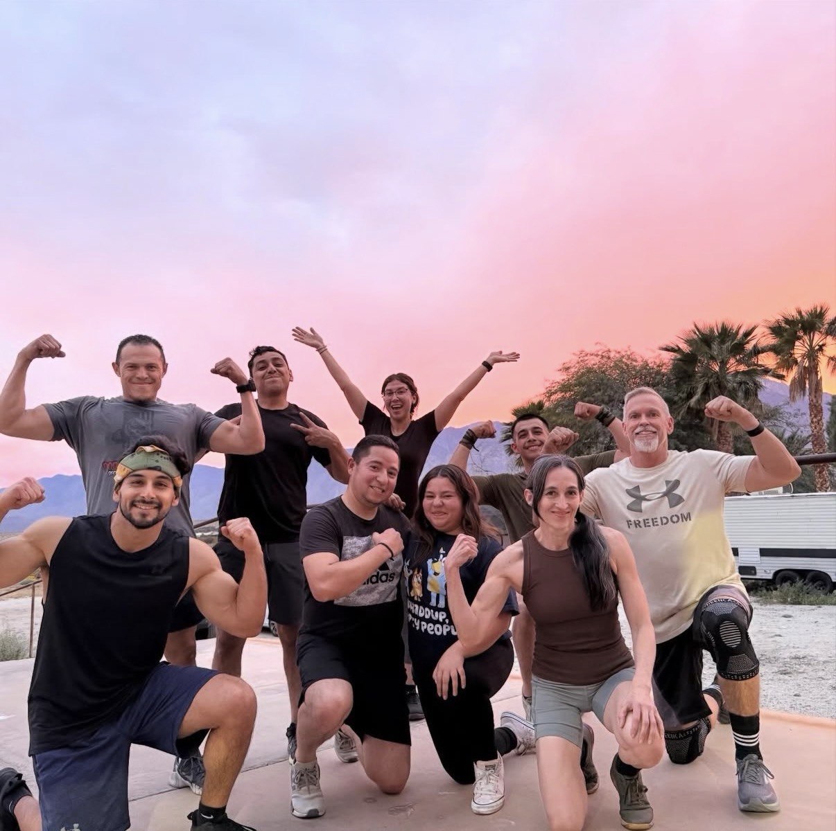 Members flexing together at sunset after an outdoor workout