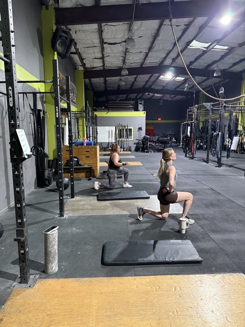 Two members working through walking lunges on the gym floor