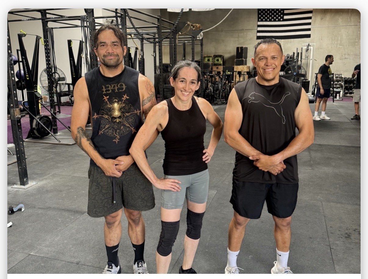 Three members posing together on the gym floor
