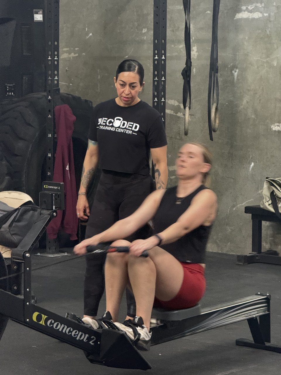 Coach guiding a member through her rowing form