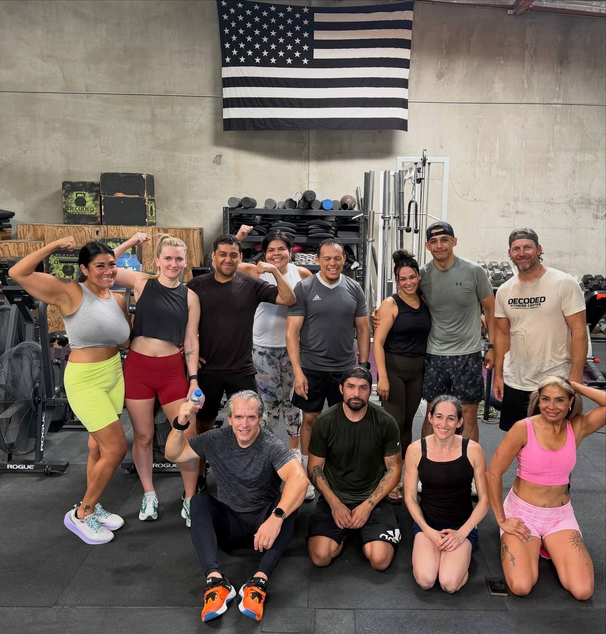 Big group photo of members flexing and smiling after class under the American flag