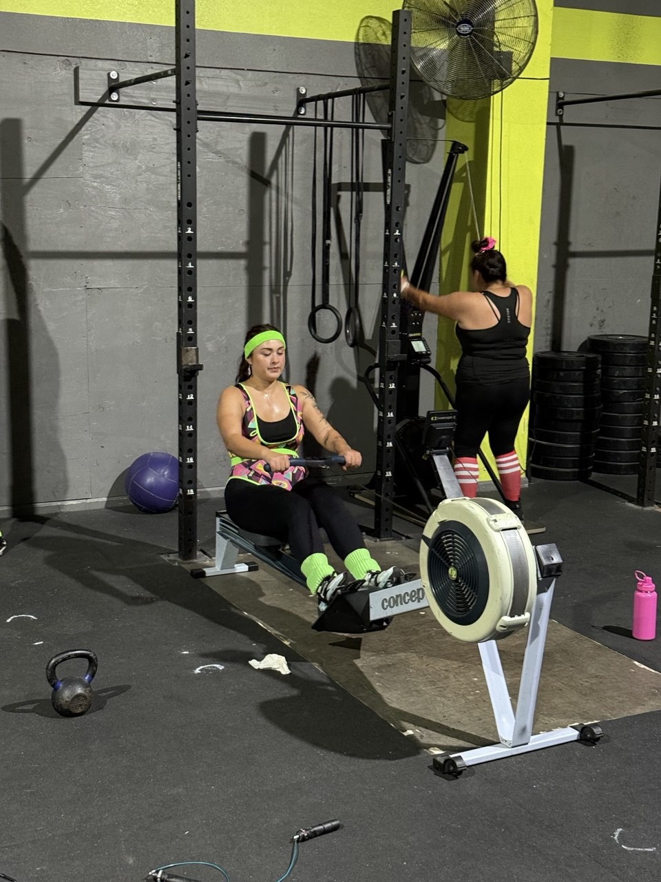 First Friday member rowing on the erg in neon