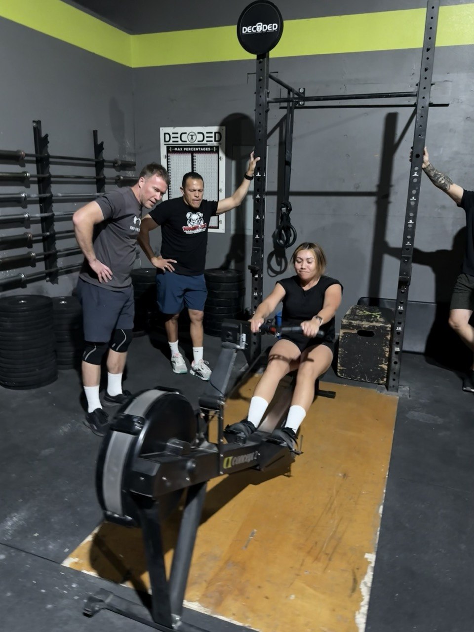 First Friday member grinding on the rower while the crew cheers her on